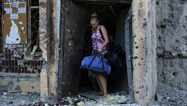 Женщина выходит из разрушенного дома в Донецке