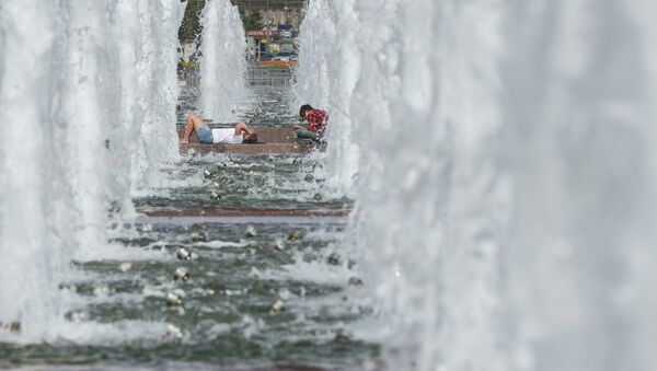 Жители Москвы спасаются от жары у фонтана на Поклонной горе