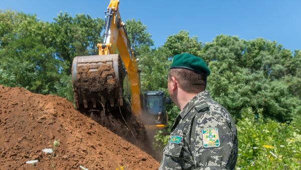 Экскаватор роет ров на границе между Украиной и Россией