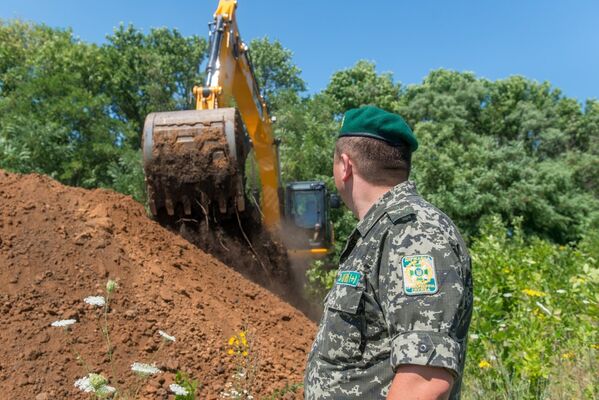 Экскаватор роет ров на границе между Украиной и Россией