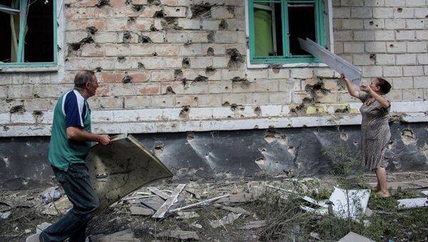 Местные жители после попадания мины во двор жилого дома во время боя в городе Шахтерск под Донецком