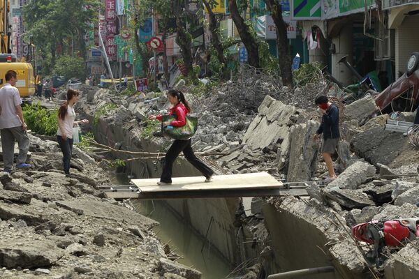 Женщина переходит траншею, образовавшуюся в результате взрыва газа в городе Гаосюн, Тайвань