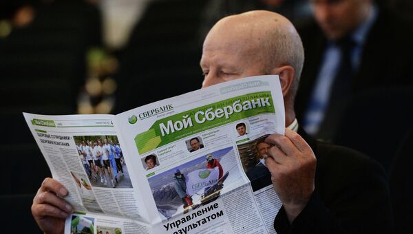 Мужщина читает газету Сбербанка России. Архивное фото