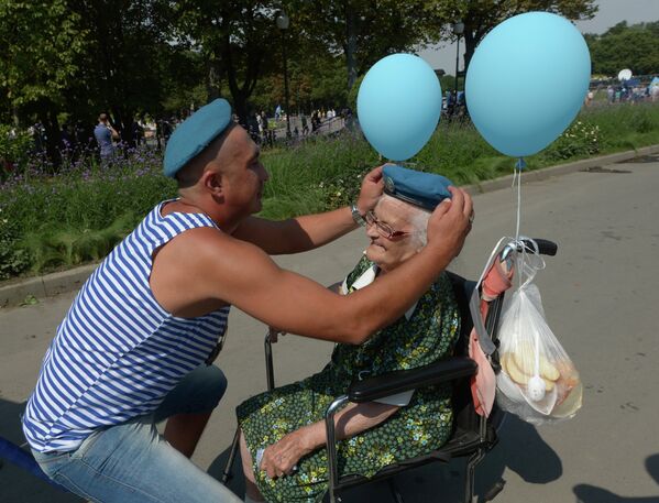 Бывший десантник одевает голубой берет пенсионерке во время празднования Дня Воздушно-десантных войск