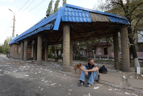 Мужчина сидит возле разрушенной остановки в Горловке