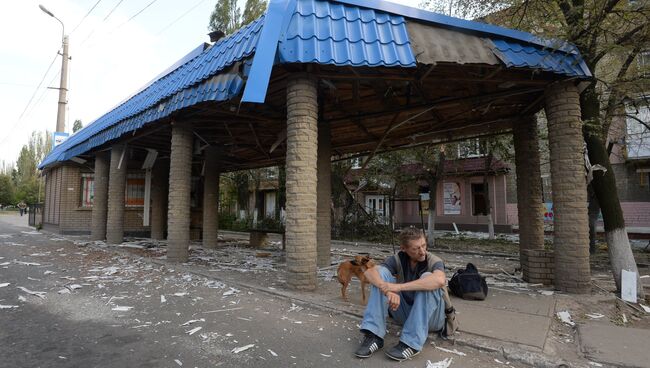 Мужчина сидит возле разрушенной остановки в Горловке