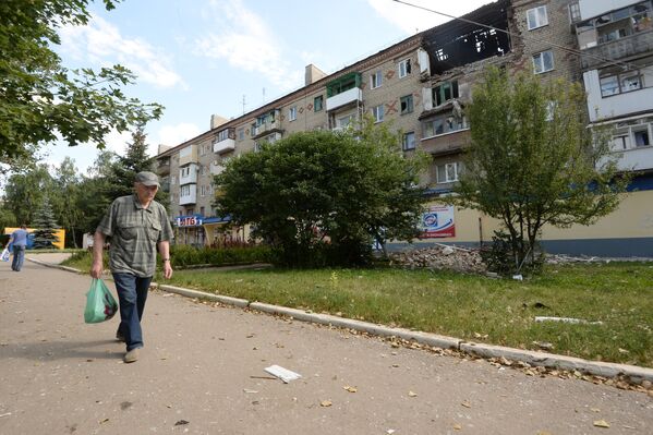 Мужчина идет возле поврежденного жилого дома в Горловке