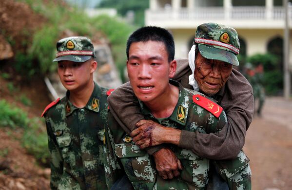Военный медик несет раненого старика в провинции Юньнань, Китай