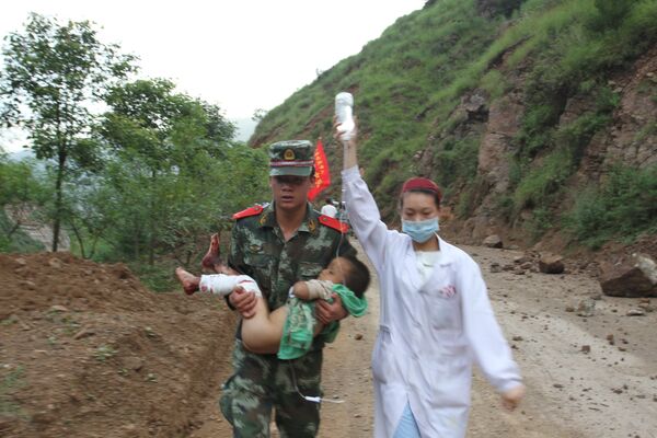 Военный и медсестра несут раненого в результате землетрясения ребенка
