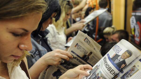 Люди читают газеты в метро в Киеве, Украина. Архивное фото