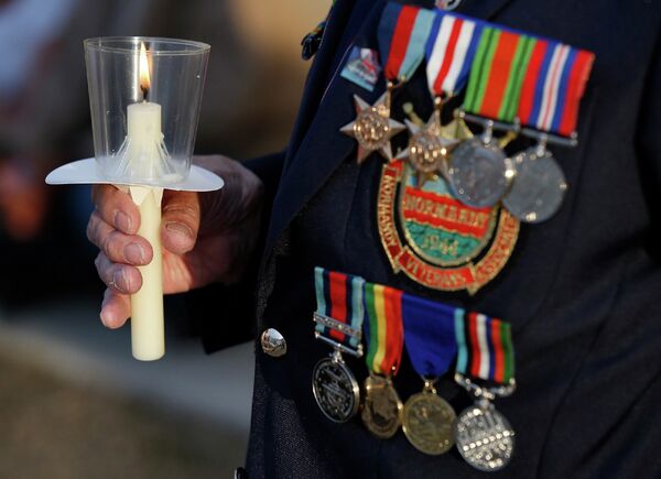 Участник церемонии, посвященной столетию с начала Первой Мировой войны, держит свечу памяти