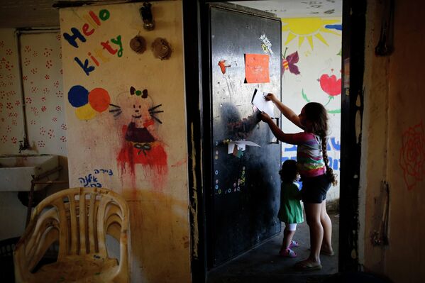 Израильские девочки вешают рисунок на дверь в бомбоубежище в Ашкелоне