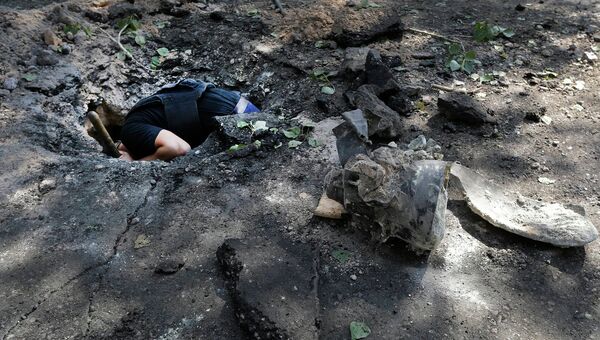 Сапер обследует воронку на месте падения снаряда в Донецке. Архивное фото