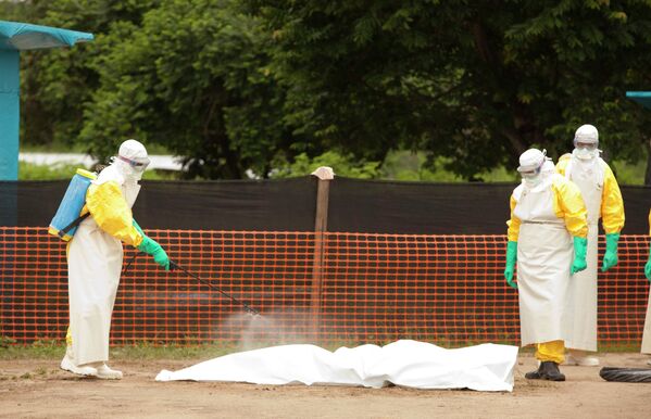 Медики дезинфицируют тело умершего от вируса эбола в Либерии
