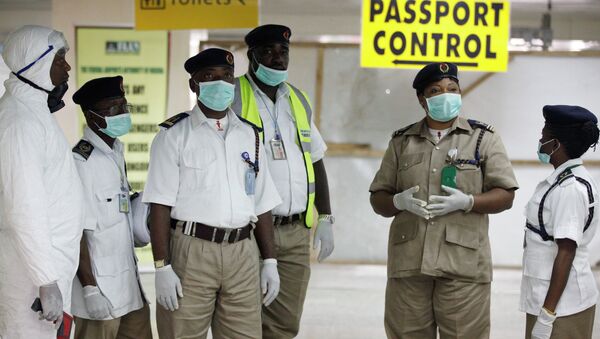 Сотрудники службы охраны здоровья ждут прибытия пассажиров в аэропорту Нигерии