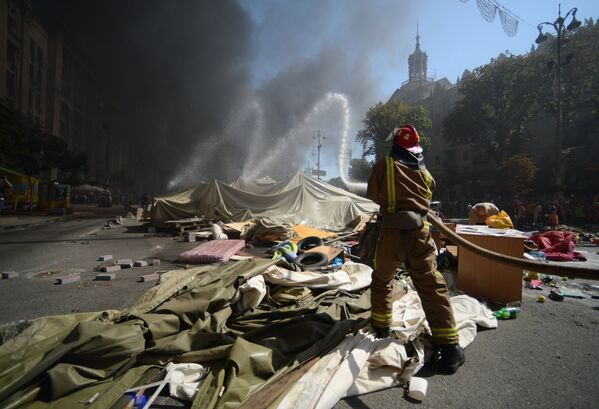 Пожарный тушит подожженные активистами покрышки на площади Независимости в Киеве