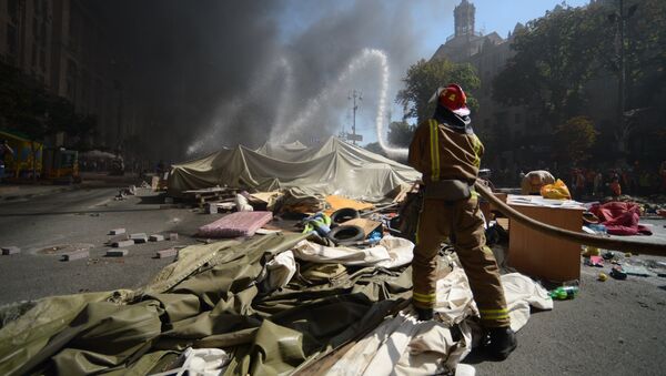 Пожарный тушит подожженные активистами покрышки на площади Независимости в Киеве