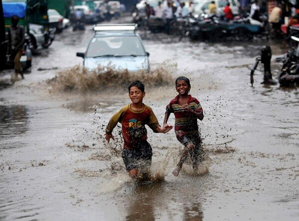 Мальчики бегут по затопленной в результате проливных дождей улице в Нью-Дели, Индия