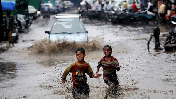 Мальчики бегут по затопленной в результате проливных дождей улице в Нью-Дели, Индия