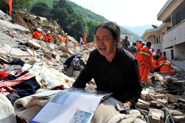 Женщина плачет на обломках своего дома, разрушенного в результате землетрясения