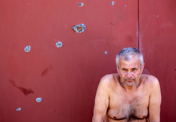 Мужчина у ворот своего дома, разрушенного в результате артобстрела в Славянске