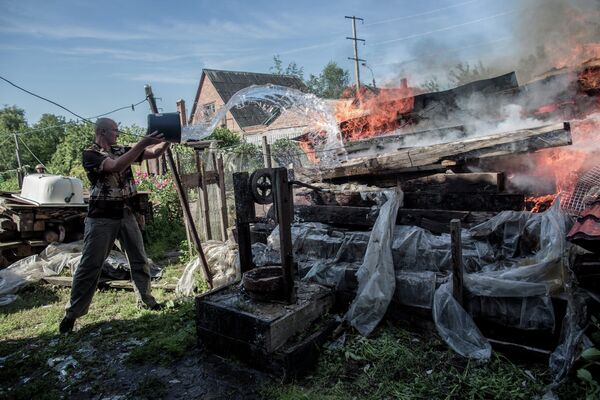 Мужчина тушит пожар после артобстрела Славянска