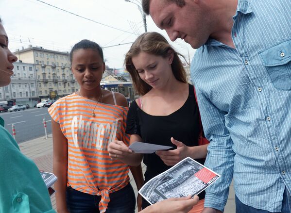 Люди рассматривают листовки-фотографии розданные в поддержку фотокорреспондента Андрея Cтенина