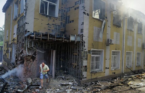 Мужчина выбегает из разрушенного в результате обстрела украинскими силовиками дома в Донецке