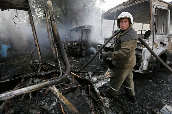 Пожарный тушит автобусы, загоревшиеся в результате обстрела Донецка украинскими военными