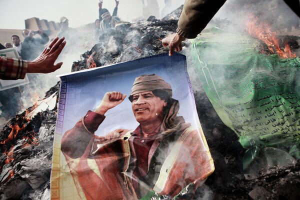 Житель Бенгази сжигает портрет Муаммара Каддафи