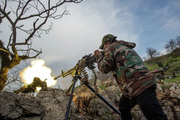 Военнослужащий правительственной армии Сирии ведет огонь из пулемета на позиции войск на одной из вершин возле города Кесаб