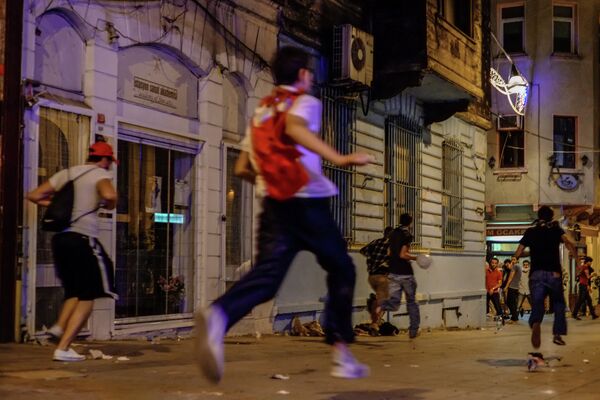 Протестующий бежит от полиции по улице в Стамбуле