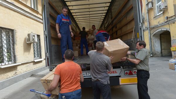 Рабочие загружают в грузовой автомобиль гуманитарную помощь для граждан Украины