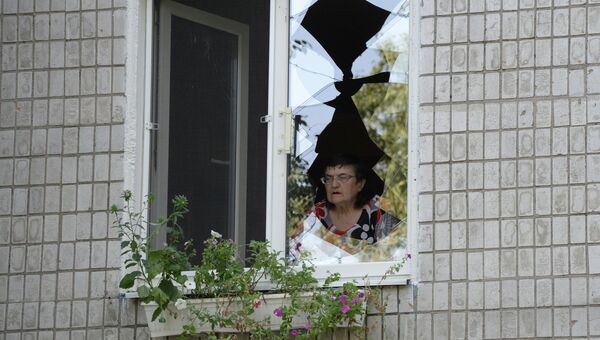 Женщина смотрит через разбитое стекло после обстрела украинской армией. Архивное фото