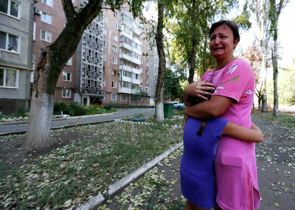 Женщина с ребенком рядом с разрушенным в результате обстрела жилым домом в Донецке