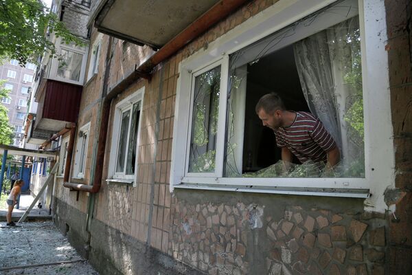 Местный житель осматривают повреждения после обстрела жилого дома в Донецке