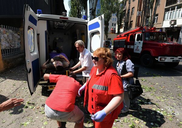 Медицинские работники транспортируют женщину, пострадавшую во время обстрела в Донецке