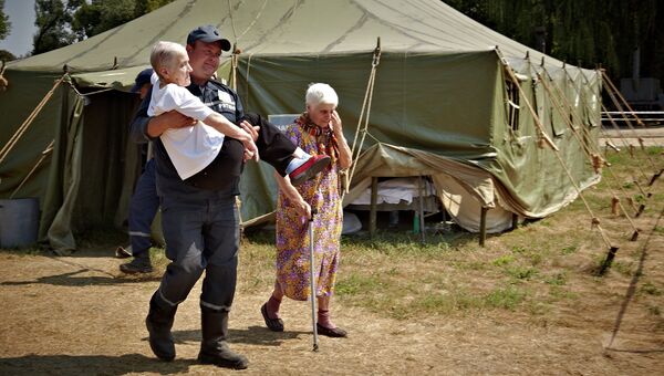 Сотрудник МЧС Украины переносит пожилую женщину, приехавшую из зоны силовой операции киевских властей на востоке Украины. Архивное фото