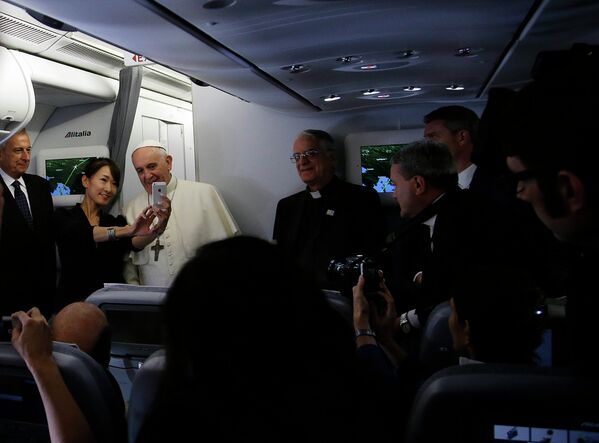 Папа Римский Франциск фотографируется с журналистами на борту самолета на пути в Сеул