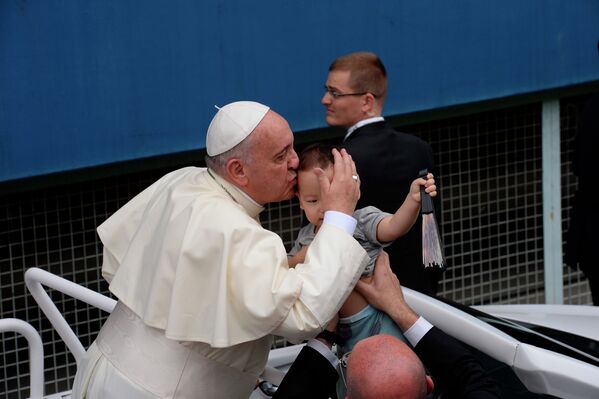 Папа Римский Франциск целует ребенка перед началом мессы на стадионе Тэджон в Сеуле