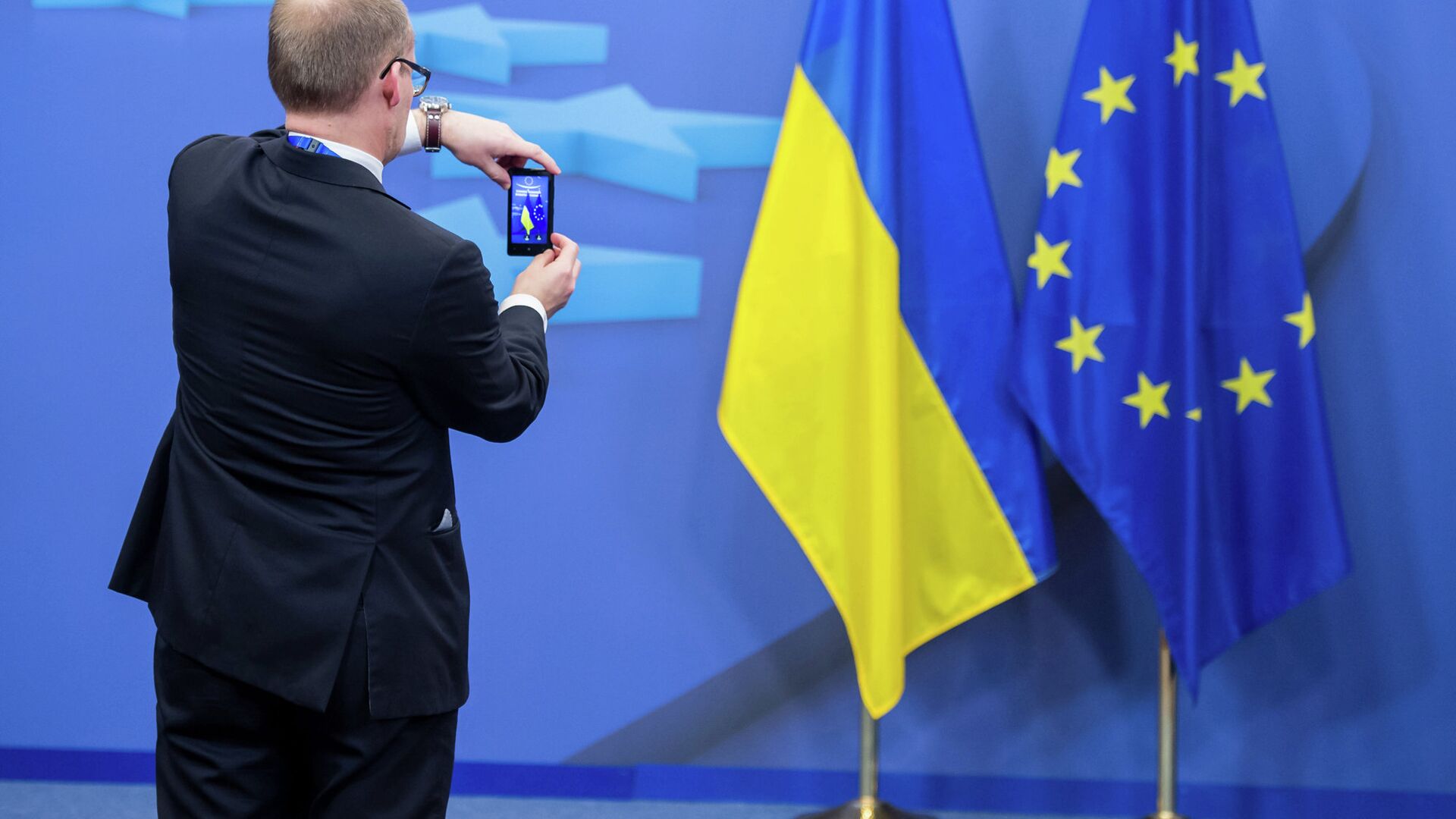 Человек фотографирует флаги Украины и Евросоюза - РИА Новости, 1920, 18.06.2022
