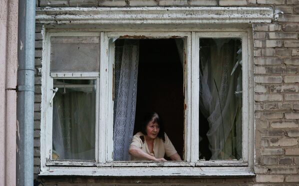Женщина в окне квартиры после обстрела украинскими военными Донецка