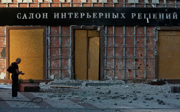 Житель Донецка стоит перед зданием, поврежденным в результате обстрела украинскими военными