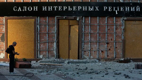 Житель Донецка стоит перед зданием, поврежденным в результате обстрела украинскими военными