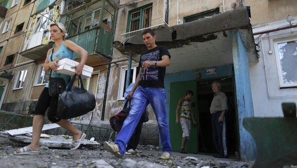 Местные жители выносят вещи из поврежденного в результате обстрела жилого дома в Донецке