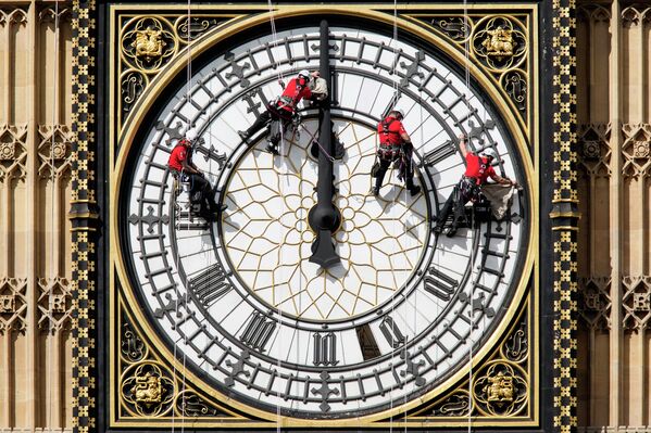 Рабочие чистят циферблат часов на Часовой башне здания Парламента в Лондоне