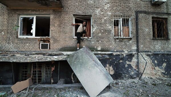Мужчина выбирается через окно жилого дома в Донецке