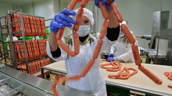 Рабочий упаковывает продукцию на фабрике мясной гастрономии