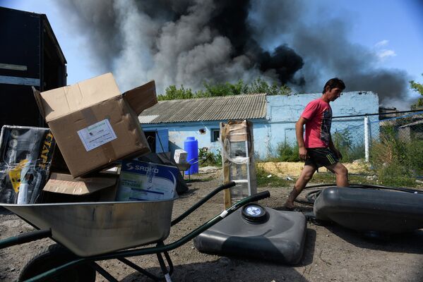 Местный житель выносит вещи из горящего дома в Петровском районе Донецка