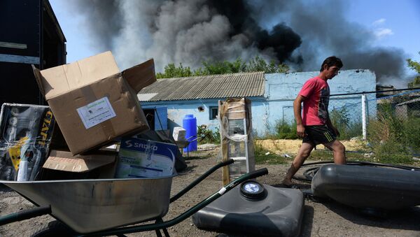 Местный житель выносит вещи из горящего дома в Петровском районе Донецка